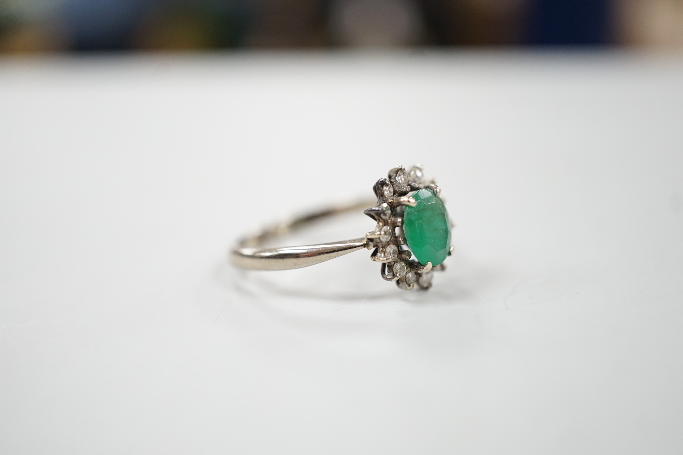 An 18ct, emerald and diamond set oval cluster ring, size O/P, gross weight 3.2 grams.